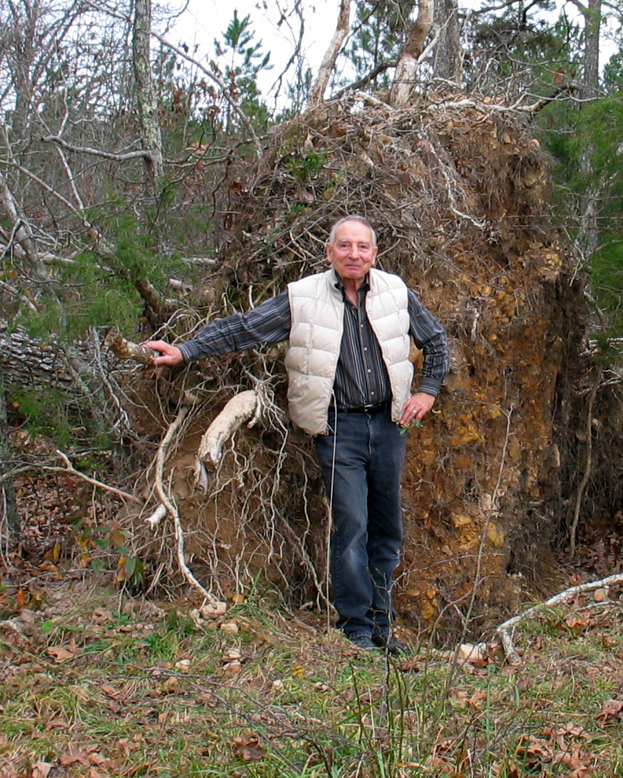 Dave Hartig stand next to a large uprooted tree