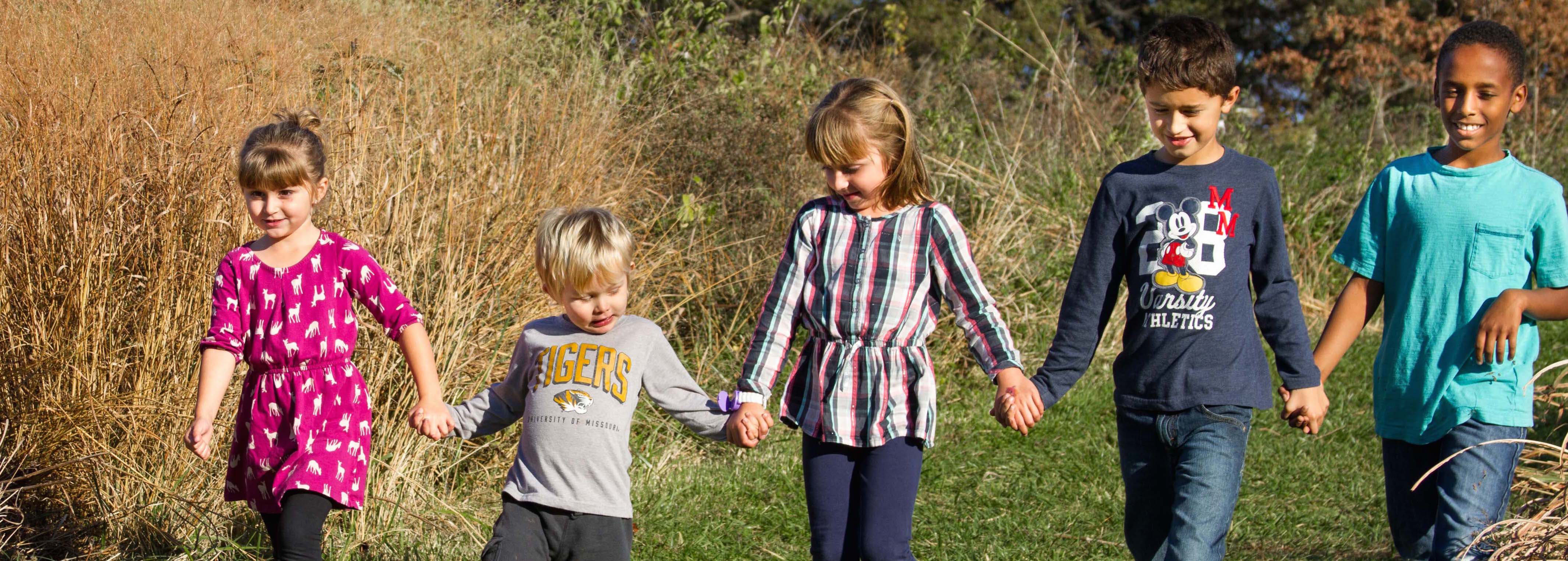 children-hold-hands-an-walk-a-green-path