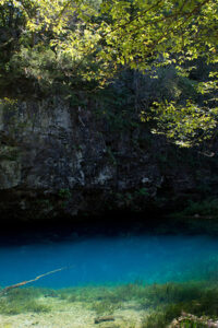 Turquoise blue spring with cliffs beside it