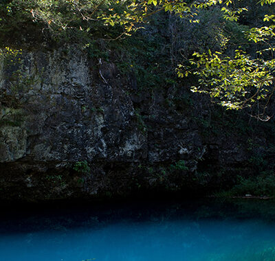 Turquoise blue spring with cliffs beside it